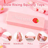 Pink strawberry squishy toy demonstrating press, squeeze, pull, and twist actions.