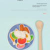 A wooden spoon is shown next to a plate filled with various colorful fruits and vegetables for a Montessori feeding game.