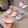 A collection of pink and light gray knit bear booties for babies, shown on a table and in a hand.