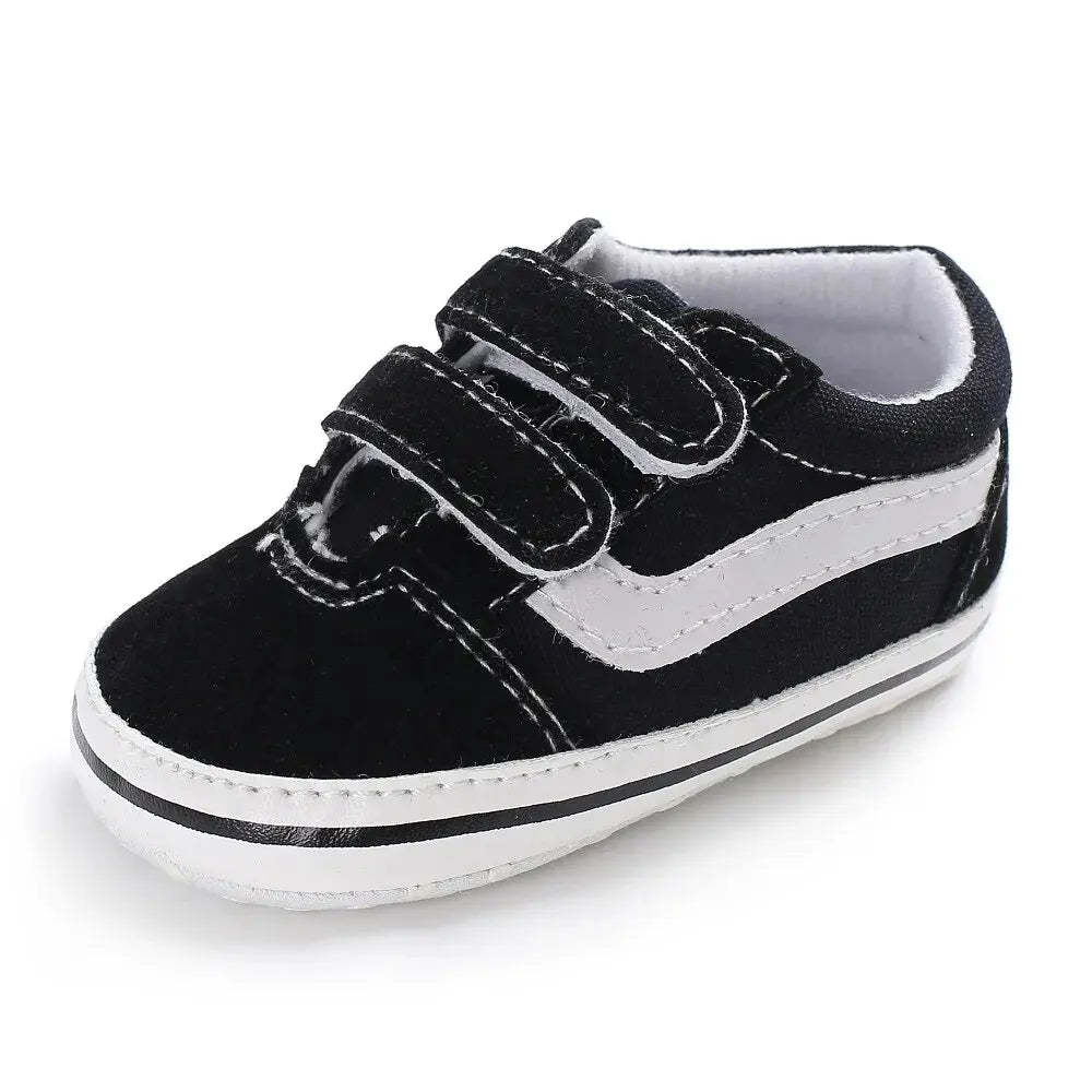 A pair of black and white striped baby canvas sneakers with a soft anti-slip design.