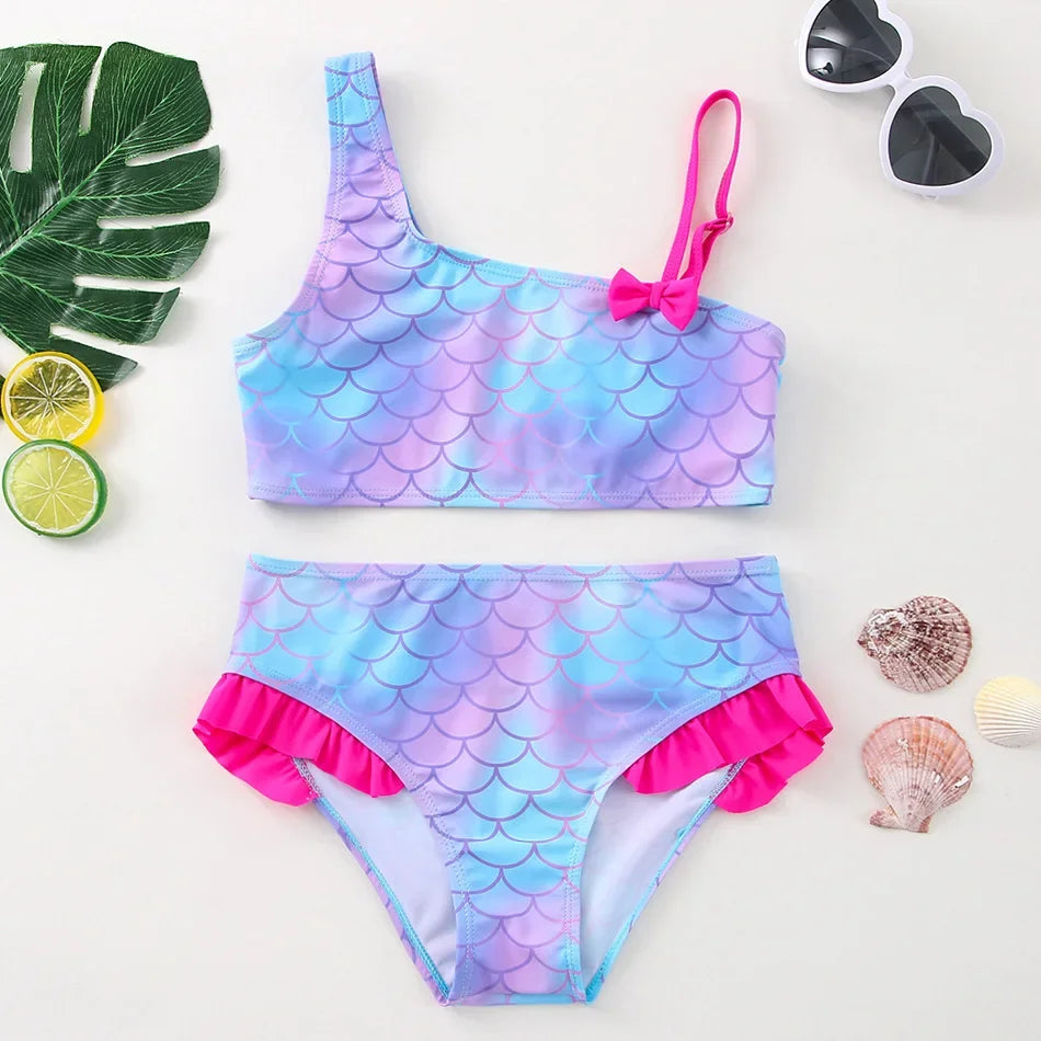 A vibrant purple and blue two-piece swimsuit set for girls featuring scale patterns and pink trim.