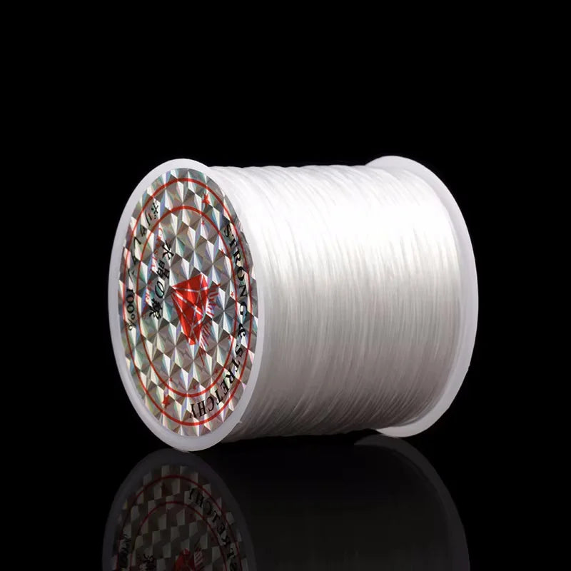 A white spool of elastic beading cord for stretch bracelets and necklaces is shown against a black background.