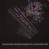 A collection of handmade beaded needles in various colors and sizes laid out on a dark surface.