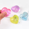 Three heart-shaped squishy toys in pink, purple, and blue glitter are shown being held by a hand.