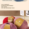A close-up of pink and red merino wool yarn skeins showing various colors and textures.