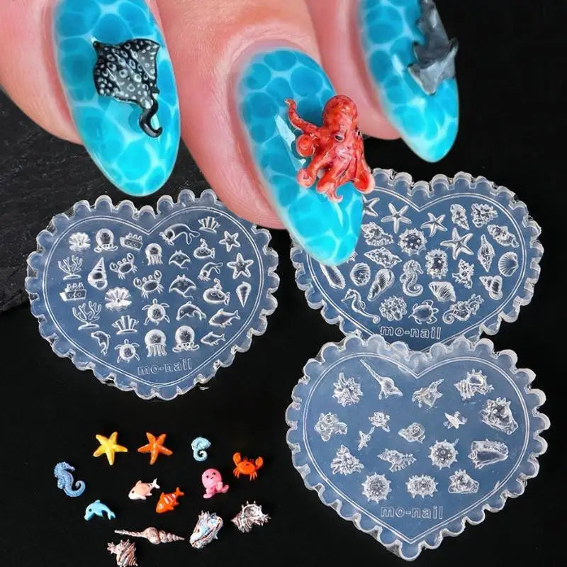 A hand holds a teal silicone nail art mold featuring sea shell, starfish, and ocean designs.