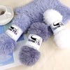 A fluffy purple and white faux fur yarn is displayed next to a cup and some printed paper.