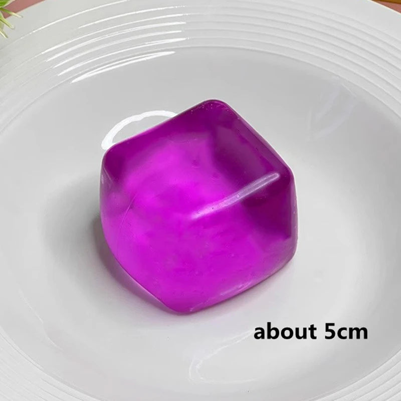 A translucent purple slow rebound ice cube sensory fidget toy resting on a white plate.