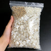 A clear plastic bag filled with assorted white and gold pearl beads and decorative accessories.