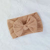 A beige knitted baby headband with a large bow shown on a white background.