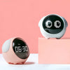 A white emoji alarm clock with a black screen and two eyes is displayed on a pink surface.