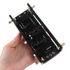 A hand holds a black beginner guitar chord trainer with tuning pegs and a sliding mechanism.