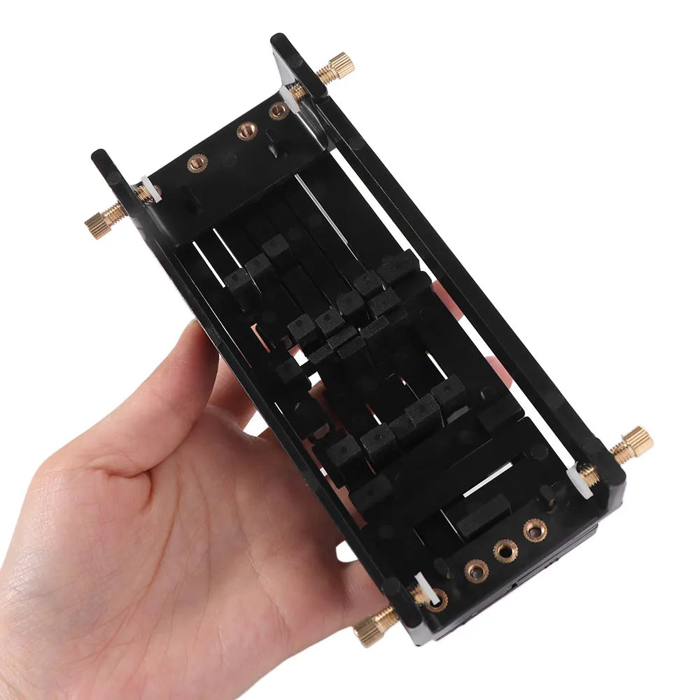 A hand holds a black beginner guitar chord trainer with tuning pegs and a sliding mechanism.
