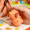 A hand holds an orange capybara squeeze toy with a bubble blowing feature on a light-colored surface.