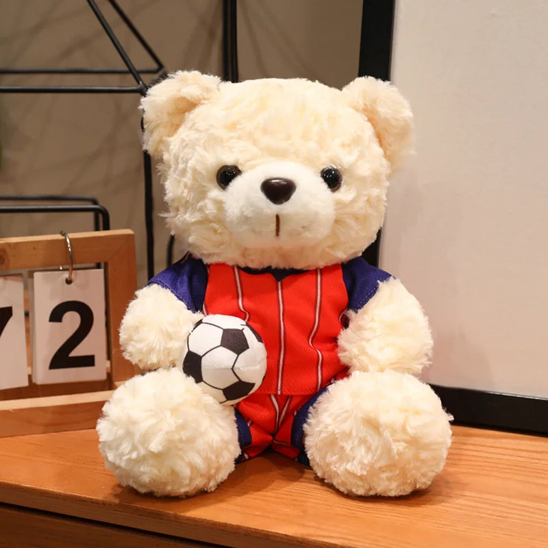 A cute bear plush toy dressed in a red and blue football uniform sitting on a wooden surface.
