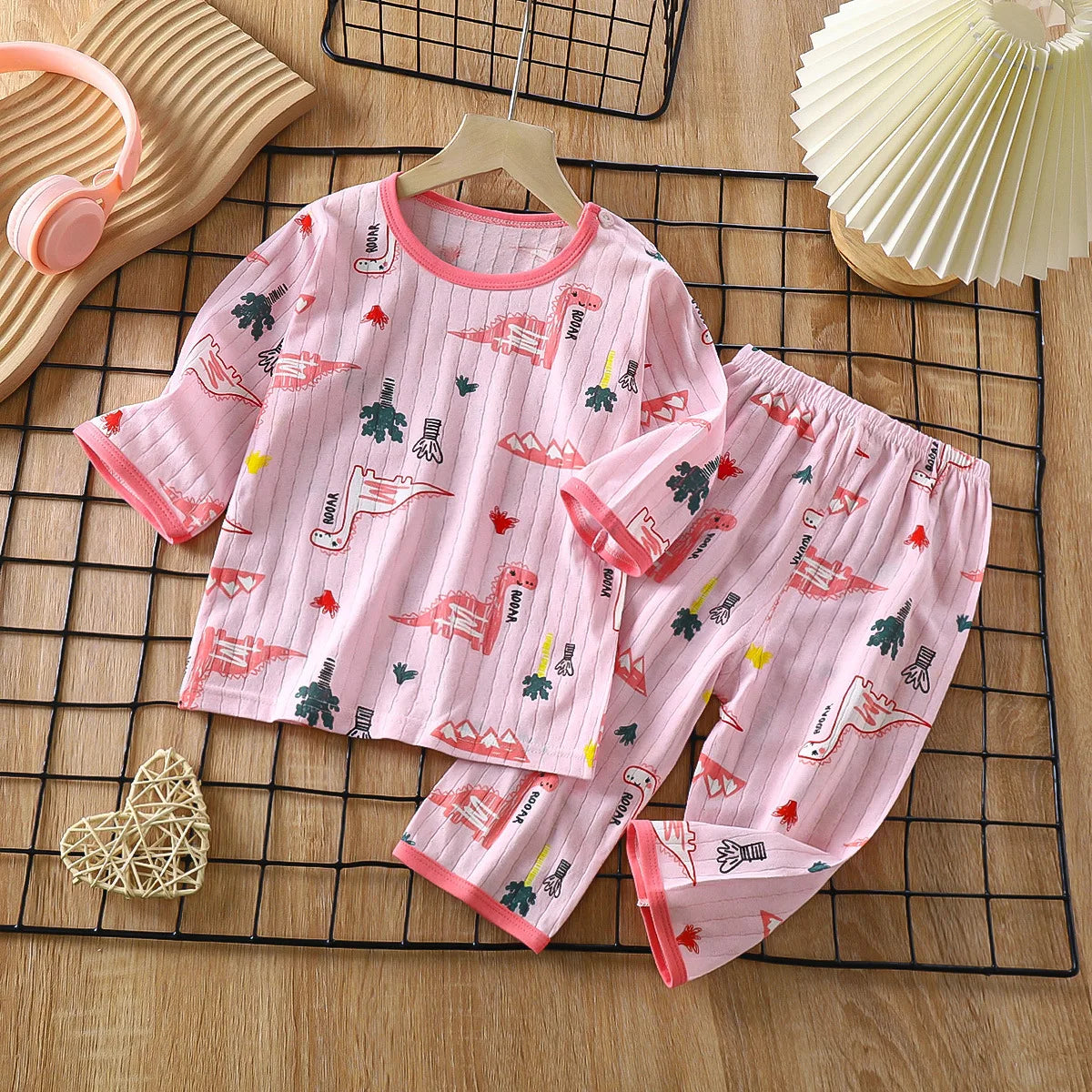 Pink long sleeve cotton pajama set for children featuring a repeating dinosaur pattern