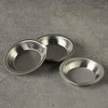 A set of three stainless steel artist paint palettes resting on a gray surface.