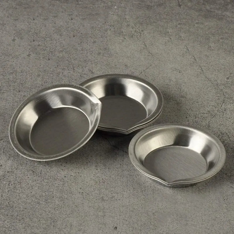 A set of three stainless steel artist paint palettes resting on a gray surface.