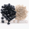 A collection of black and beige plastic safety eyes for amigurumi with locking washers displayed on a ruler.
