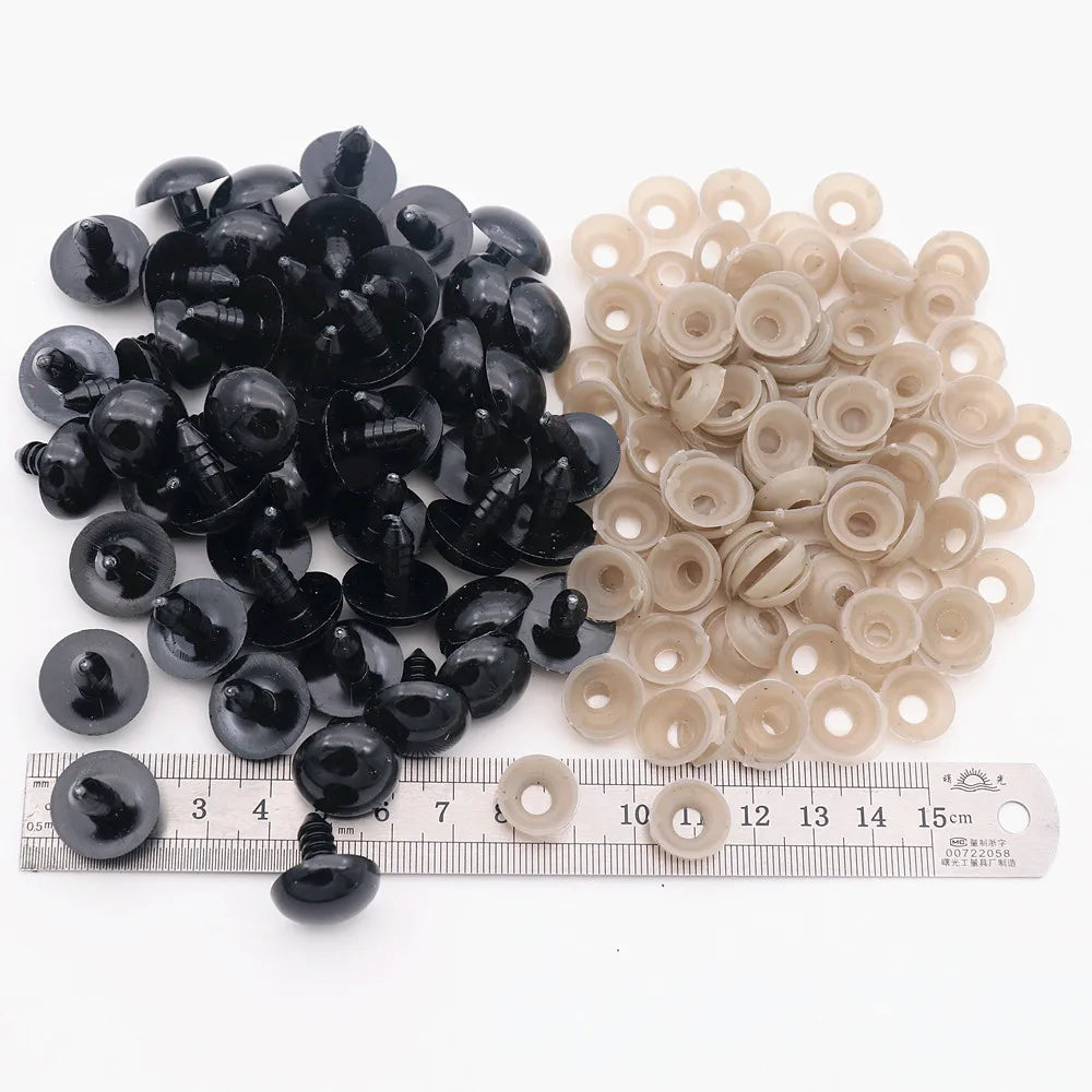 A collection of black and beige plastic safety eyes for amigurumi with locking washers displayed on a ruler.