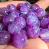 A handful of purple resin spacer beads with a starry glitter finish held in a hand.