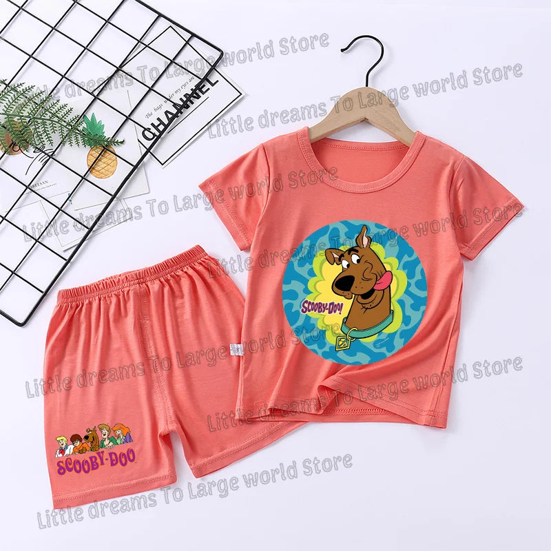 A pink Scooby-Doo pajama set featuring a short sleeve shirt and shorts with an orange and blue circular graphic.
