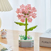 A pink rose flower building block bouquet set with green stems and leaves displayed on a wooden table.