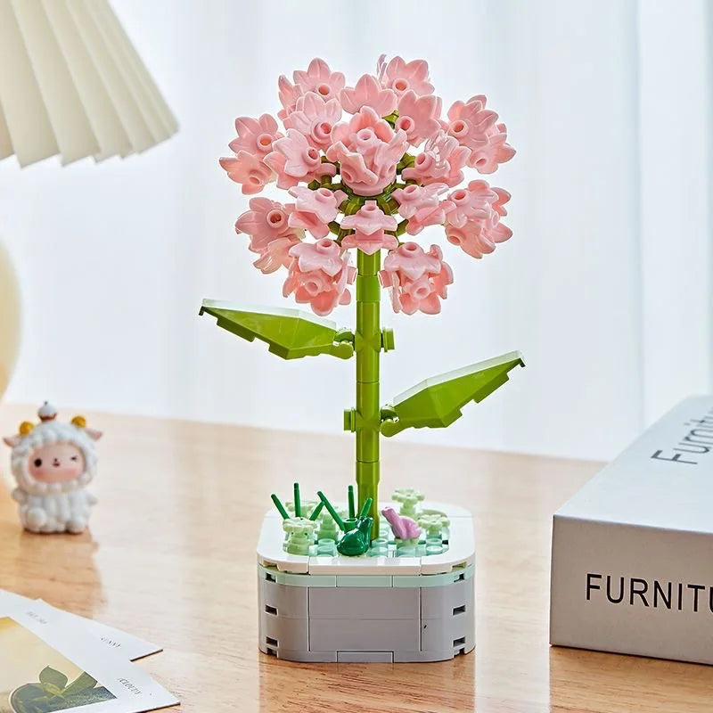 A pink rose flower building block bouquet set with green stems and leaves displayed on a wooden table.