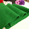 A stack of bright green felt fabric sheets rolled and laid out on a white surface.
