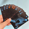 A hand holds a fan of black playing cards showing face cards like Jack, Queen, and King.