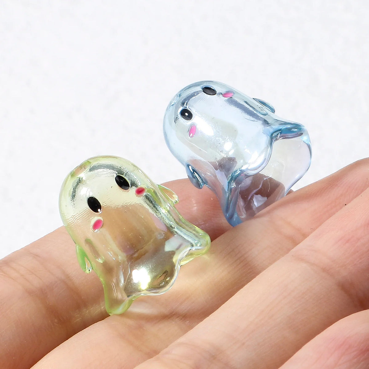 Clear acrylic ghost beads with pink accents resting on a hand