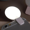 A portable LED selfie ring light is shown mounted on a smartphone for illumination.