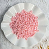 A white dish filled with pink plastic beads used as filler for DIY squishy toys and stress relief crafts