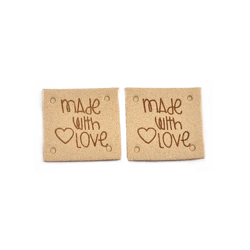 A set of two tan embossed leather labels for sewing and crafts, each engraved with Made with Love.