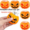A hand holds an orange pumpkin-shaped Halloween stress ball with a white ghost face inside.