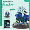 A building block kit of a blue flower arrangement featuring roses and greenery on a circular base.