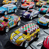 Collection de voitures jouets à tirer en métal, diverses couleurs et designs, présentées sur une surface sombre.