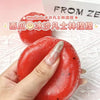 A hand holds a red watermelon squishy stress ball fidget toy against a white background.