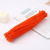 A bright orange bundle of chenille craft stems is displayed next to a notebook titled Minimalism.