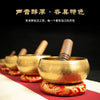 A golden copper singing bowl with a mallet is displayed on a red cloth, emphasizing its sound and artistic features.