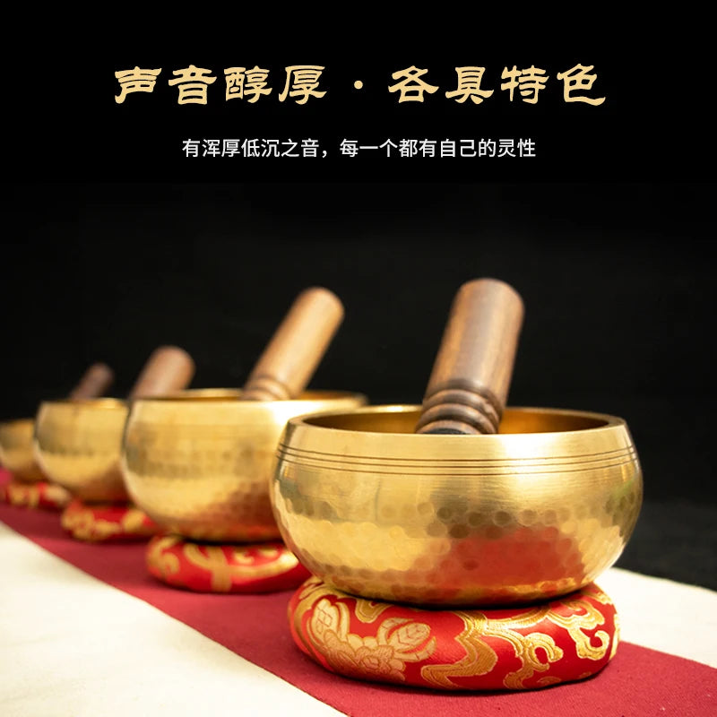 A golden copper singing bowl with a mallet is displayed on a red cloth, emphasizing its sound and artistic features.