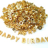A pile of gold-colored acrylic alphabet letter beads for jewelry making and crafts