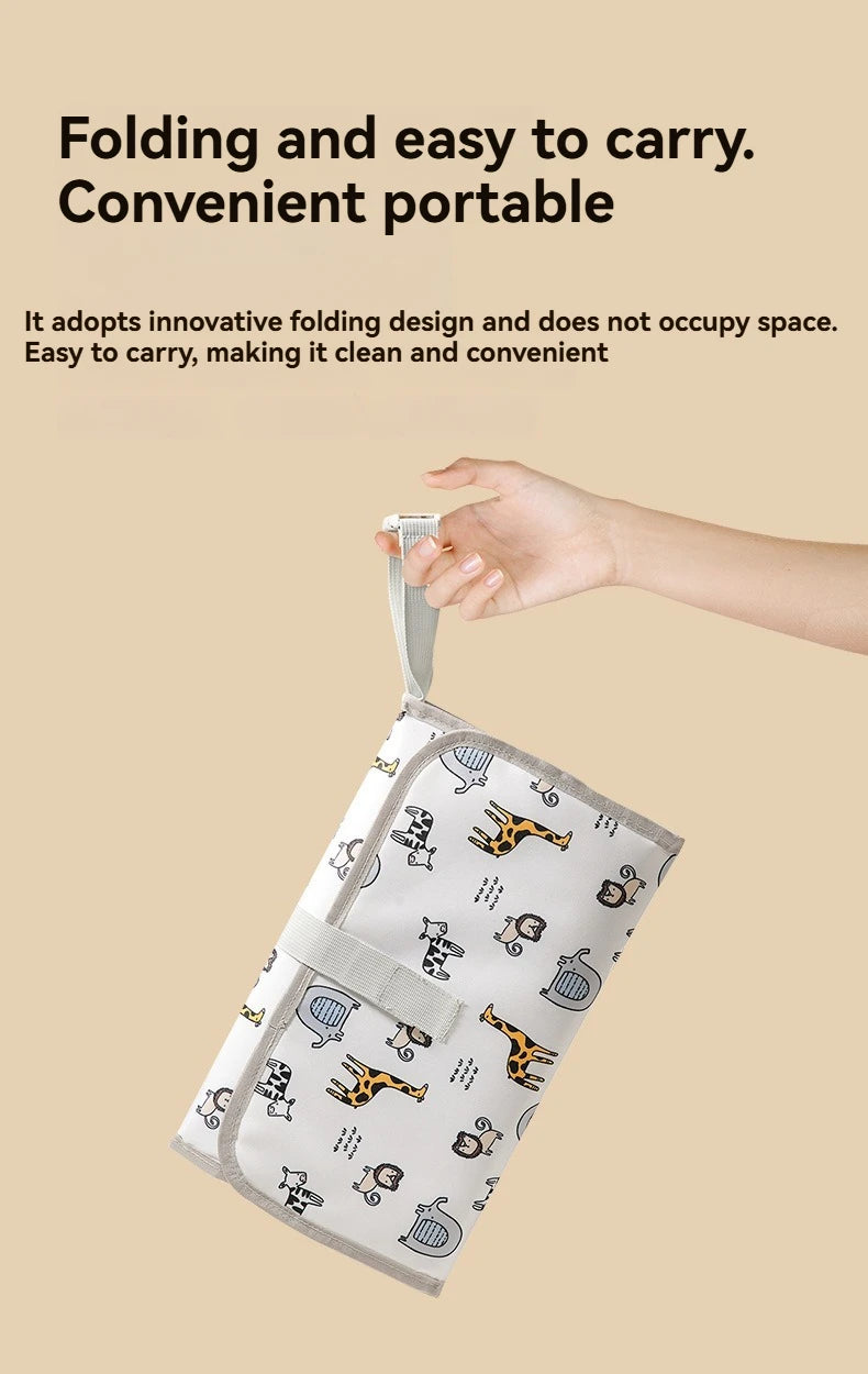 A hand is holding a folded portable baby changing mat with a carry handle, demonstrating its convenient and foldable design.