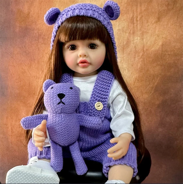 A purple silicone baby doll wearing a matching hat and vest with long brown hair.