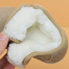 A hand holds a tan leather winter boot with a thick white faux fur lining.