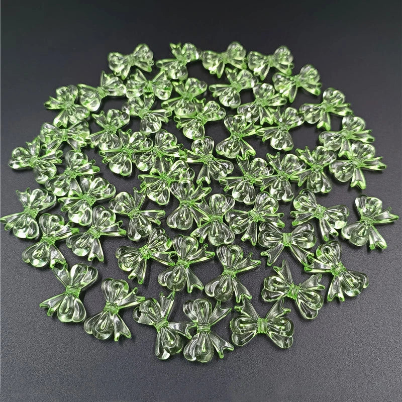 A pile of 20 clear green acrylic bow beads for jewelry making