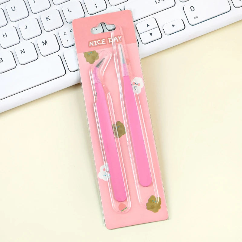 A pink case holding a pair of precision stainless steel tweezers for nail art and makeup, resting on a white keyboard.