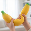 Hands holding a yellow banana squishy stress relief toy with green tips