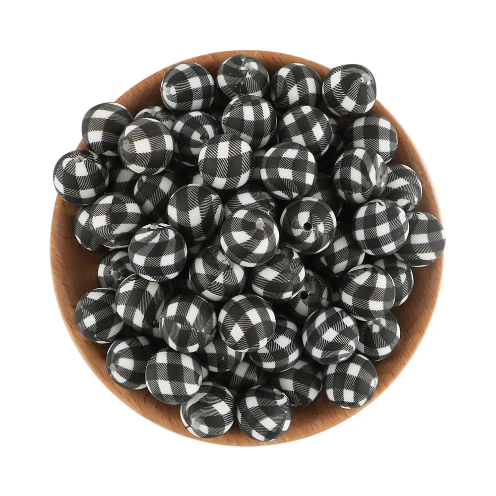 A pile of black and white plaid silicone beads for jewelry making in a wooden bowl.