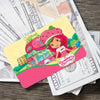 A pink card featuring a cute strawberry and shortcake character on a background of currency.